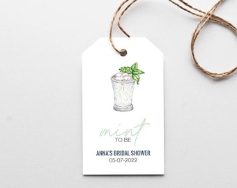 May include: A white tag with a green mint julep illustration and the text "mint to be" in green script. Below the illustration is the text "Anna's Bridal Shower" in blue and the date "05-07-2022" in black.