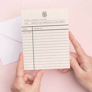 May include: A white card with black lines and blue accents. The card has the text "AUTHOR: ALEXANDRA & WILLIAN" and "TITLE: THANK YOU FOR CELEBRATING OUR NEXT CHAPTER". The date "09.24.2022" is printed on the card.