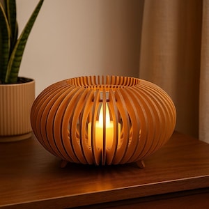 May include: A wooden candle holder with a warm, inviting glow. The holder is made of vertical wooden slats, creating an open, spherical design. A lit candle is visible inside, casting a soft light. The candle holder sits on a wooden surface.