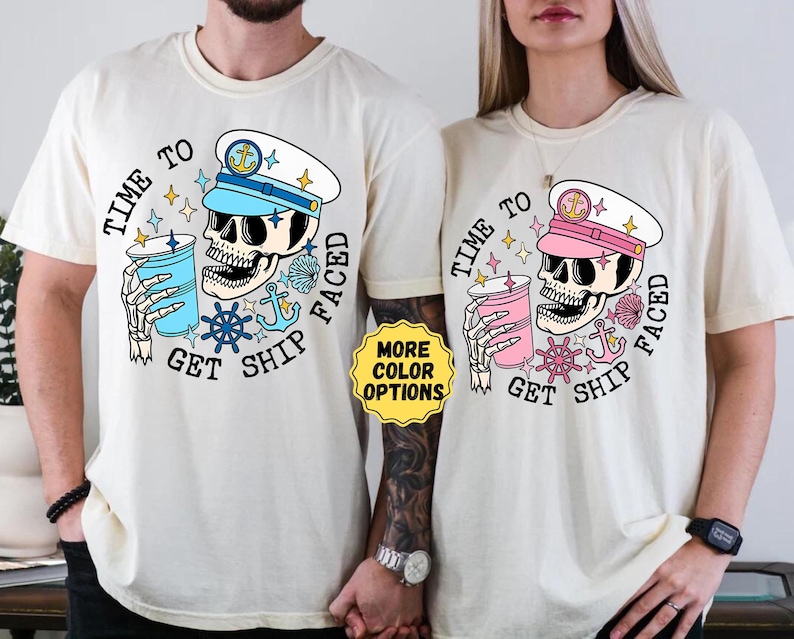 May include: Two cream-colored t-shirts with a graphic design. The design features a skull wearing a sailor hat and holding a drink. The text reads 'TIME TO GET SHIP FACED' in a circular arrangement. The skull and drink colors vary between blue and pink.