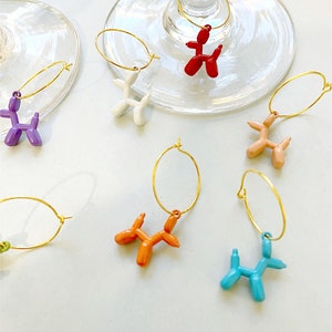Pu&ograve; includere: Set di sei ciondoli per bicchieri da vino a forma di palloncino a forma di cane colorati. Ogni ciondolo &egrave; attaccato a un anello dorato. I ciondoli sono di colore rosso, bianco, viola, pesca, arancione e blu.