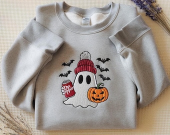 May include: A light gray sweatshirt featuring a Halloween-themed embroidered design. The design includes a ghost wearing a red beanie, holding a Dr. Pepper can, and a jack-o'-lantern. Black bats are embroidered around the ghost.