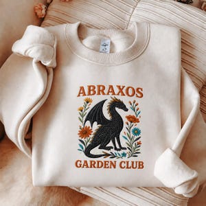 刺繍入りアブラクソスガーデンクラブスウェットシャツ、スローンオブグラスクルーネック、マノンブラックビークシャツ、TOGブックラバーギフト、フローラルドラゴンシャツ
