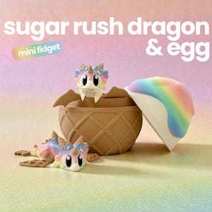 May include: A sugar rush dragon & egg mini fidget toy set. One dragon sits inside a brown waffle-textured bowl, while another lies in front. The egg top is rainbow-coloured with a white base. The dragons feature pastel rainbow scales and horns.