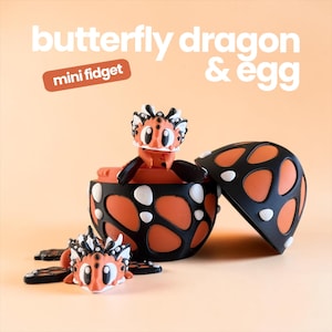 May include: A butterfly dragon and egg mini fidget toy. The dragon is orange, black, and white with large eyes. One dragon sits inside a black and orange egg shell, while another lies in front. Text reads: butterfly dragon & egg mini fidget.