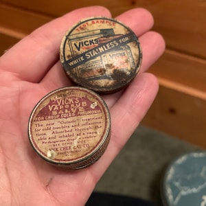 May include: Two vintage tin containers of Vicks VapoRub, one labeled "Vicks VapoRub Salve for Croup Colds, Pneumonia" and the other labeled "Vicks White Stainless for Inflammation Congestion".