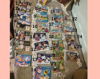 May include: A collection of colorful, rectangular cards featuring various cartoon characters and animals. The cards have different designs, including a rainbow, a rocket, and various animals. The cards are arranged on a lace tablecloth.