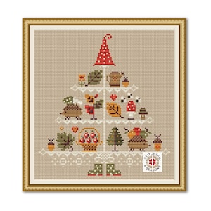 May include: Cross-stitch design in a gold frame, featuring a whimsical tree shape filled with autumn-themed elements. Includes a red and white mushroom-shaped hat, a hedgehog, a basket of berries, and a variety of leaves and mushrooms. The design is on a tan background.