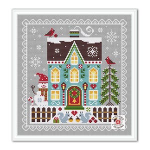 May include: A cross-stitch pattern depicting a blue and white house with a red door and a snowman in front. The house has a brown roof and white trim. There are two trees on either side of the house, one with a red cardinal on top. The pattern is surrounded by a white border with a grey background.