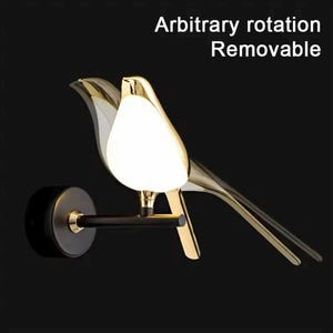 May include: A gold bird-shaped wall sconce with a white light fixture. The sconce is mounted on a black wall bracket. The text "Arbitrary rotation Removable" is visible above the sconce.