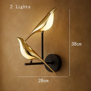 May include: Gold bird-shaped wall sconces with black metal accents. The sconces are mounted on a wall and feature two lights. The sconces are 28 inches wide and 38 inches tall. 2 lights.
