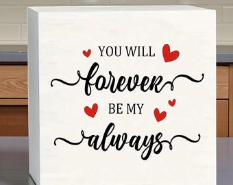 Letrero de madera con mensaje de amor para San Valentín: "Serás mi amor por siempre" con decoración de corazones rojos.