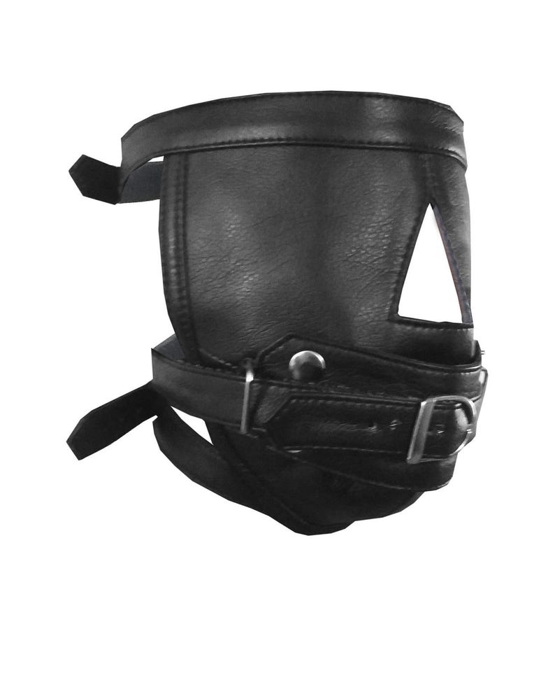 Op de afbeelding: Zwart leren masker met een driehoekige uitsparing boven het oog en verstelbare bandjes. Het masker heeft een gespsluiting en is ontworpen om rond het gezicht te passen. Het leer heeft een getextureerde uitstraling.