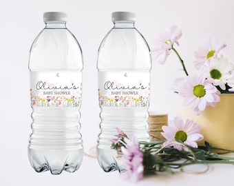 Op de afbeelding: Twee doorzichtige plastic waterflessen met gepersonaliseerde etiketten. De etiketten hebben een bloemenmotief met de tekst "Olivia's Baby Shower".