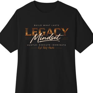 May include: Black t-shirt with the words "LEGACY Mindset" in a gold, textured font. The shirt also features the phrases "BUILD WHAT LASTS", "HUSTLE. EXECUTE. DOMINATE." and "Est. Self-Made" in a gold color.