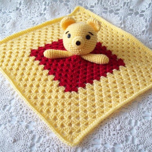 May include: A yellow and red crocheted baby blanket with a crocheted Winnie the Pooh bear in the center.