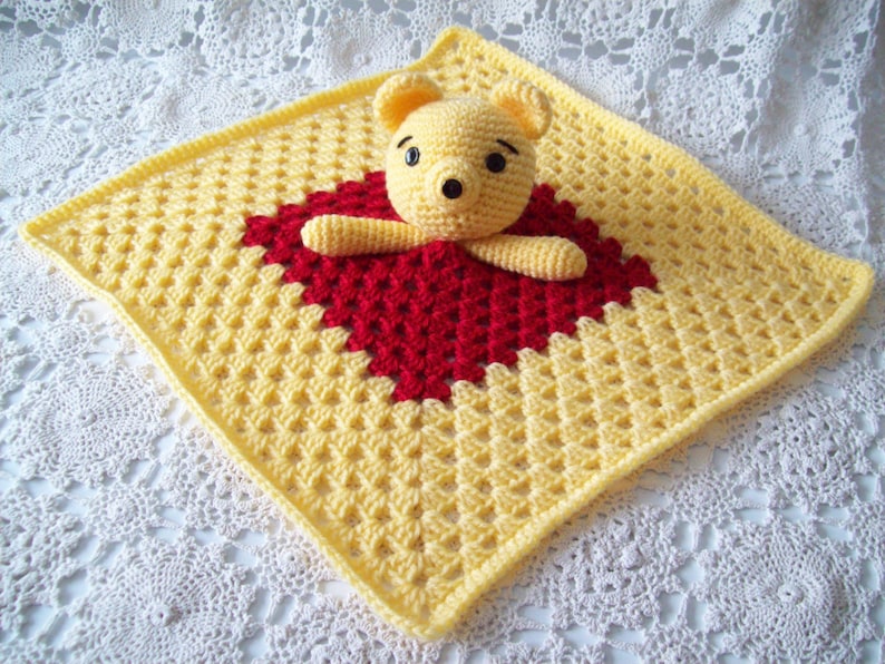 May include: A yellow and red crocheted baby blanket with a crocheted Winnie the Pooh bear in the center.