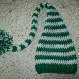 May include: Green and white striped crocheted elf hat with a long, green and white striped tail and a white pom-pom.
