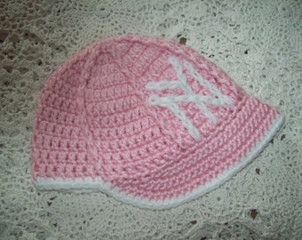 Peut inclure: Un chapeau en crochet rose avec un motif en crochet blanc. Le chapeau a une bordure et est fait avec un fil doux.