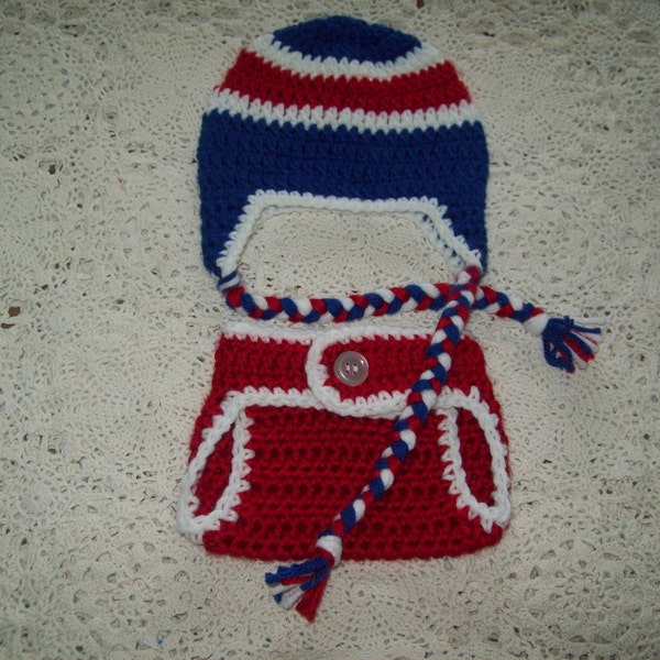 May include: Red and blue crocheted baby hat and matching outfit with a white button.
