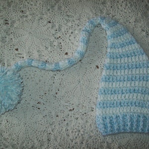 May include: A blue and white striped crocheted hat with a long tail. The hat has a pom-pom on the end of the tail.