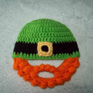 Peut inclure: Chapeau crocheté vert avec une bande noire et une boucle jaune. Le chapeau a une barbe orange crocheté attachée.