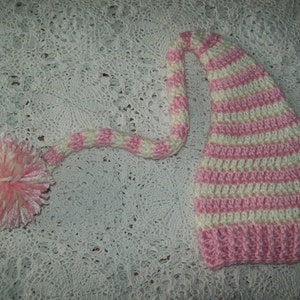 May include: Pink and white striped crocheted hat with a long tail and a pom-pom on the end.