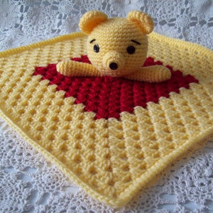 May include: A yellow and red crocheted baby blanket with a crocheted Winnie the Pooh bear in the center.