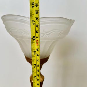 Pu&ograve; includere: Una lampada da tavolo vintage con paralume in vetro smerigliato bianco e base color oro. Il paralume presenta un motivo floreale decorativo. La lampada &egrave; alta circa 46 cm.