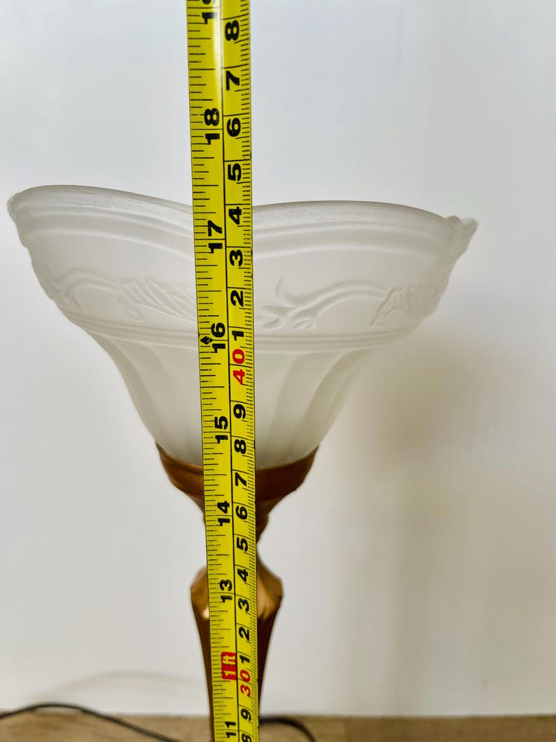 Pu&ograve; includere: Una lampada da tavolo vintage con paralume in vetro smerigliato bianco e base color oro. Il paralume presenta un motivo floreale decorativo. La lampada &egrave; alta circa 46 cm.
