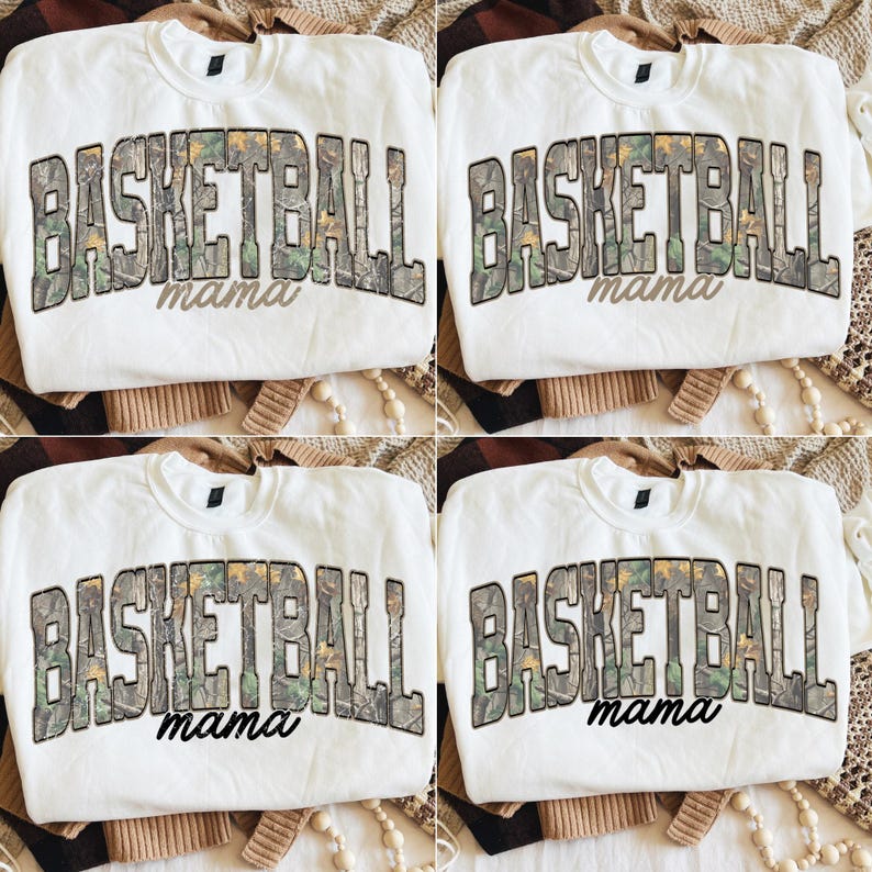 May include: Four white sweatshirts featuring the text "BASKETBALL mama" in a camouflage pattern. The sweatshirts are displayed on a neutral background. The crew neck sweatshirts are designed with a focus on the text.