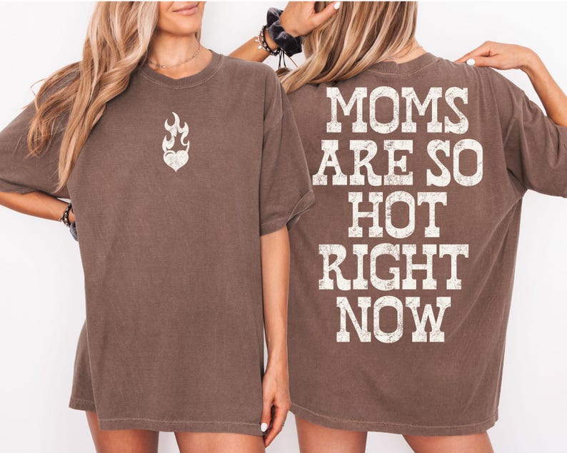 May include: Brown t-shirt with the text "MOMS ARE SO HOT RIGHT NOW" on the back. The front of the shirt features a flame heart graphic. The shirt has short sleeves and a relaxed fit.