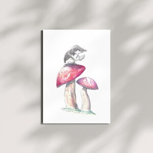 May include: Watercolor illustration of a small, gray and white animal perched atop a large red mushroom. A smaller mushroom is next to it. The artwork is on a white background.
