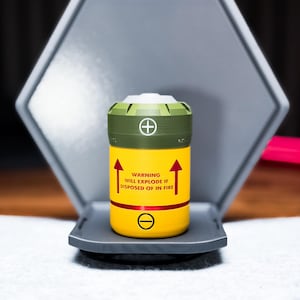 May include: A yellow and green cylindrical object with red arrows and text that reads "WARNING WILL EXPLODE IF DISPOSED OF IN FIRE." The object has a plus and minus symbol and is set in a grey hexagonal holder.