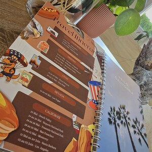 May include: A travel itinerary planner with a spiral binding. The cover features a cartoon illustration of a bear wearing a hat and holding a suitcase. The itinerary includes stops in California, Arizona, Utah, Nevada, and Los Angeles. The text "Travel Itinerary" is printed in brown on a tan background.