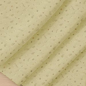 May include: A light sage green wrapping paper featuring a repeating pattern of small dark brown animal paw prints, delicate sprigs of leaves, and tiny white floral accents scattered across the surface in a soft, matte finish texture.