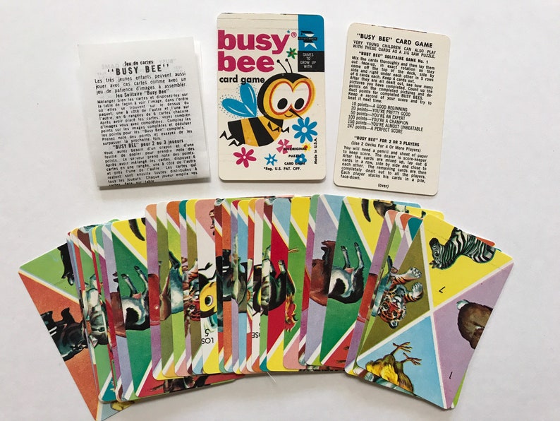 以下が含まれることがあります： 動物とミツバチのカラフルなイラストが描かれた、ビンテージカードゲーム「Busy Bee」。ゲームには説明書とカードデッキが含まれています。