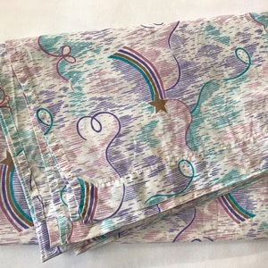 May include: A white twin-sized bed sheet with a colourful pattern of rainbows, stars, and swirls in shades of purple, pink, teal, and gold.