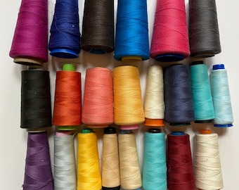 May include: A collection of 24 spools of thread in various colors, including red, blue, green, yellow, orange, pink, purple, and black. The spools are arranged in two rows, with 12 spools in each row.