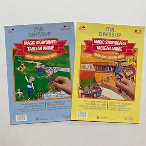 May include: Two colourful board books with illustrations of children and animals. The books are titled "Mr. Dressup Magic Storyboard Tableau Animé" and feature moveable vinyl figures. The books are for ages 3 and up.