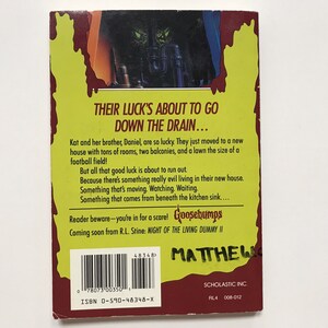 Op de afbeelding: Een gele en rode boekomslag met de titel "Their Luck's About to Go Down the Drain..." en de tekst "Goosebumps" in een wit kader. Het boek gaat over een broer en zus die verhuizen naar een nieuw huis met een heleboel kamers, twee balkons en een gazon ter grootte van een voetbalveld. De boekomslag toont een enge afbeelding van een monster met een pijp.