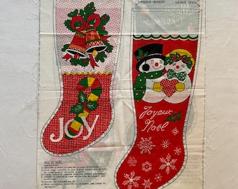 May include: A white fabric panel with two red and white Christmas stocking patterns. The stocking on the left has a red, white, and green candy cane and the word "JOY" in yellow and green letters. The stocking on the right has two snowmen holding a red heart and the words "Joyeux Noel" in red and green letters.