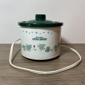 以下が含まれることがあります： 黒いハンドルと「But First, Coffee」のテキストが黒い太字で書かれた白いセラミックマグ。マグは白い表面に置かれています。