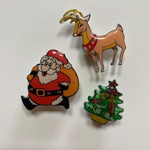 May include: Three Christmas-themed pins: a red and white Santa Claus carrying a bag of gifts, a brown reindeer with a red collar, and a green Christmas tree with red ribbon and bells.