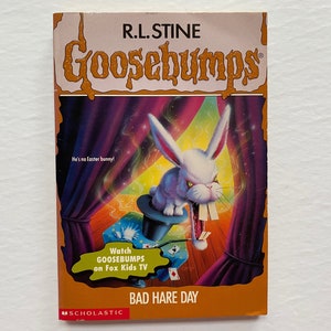 May include: A Goosebumps book cover featuring a white rabbit with sharp teeth, popping out of a top hat. The book title is "Bad Hare Day" and the author is R.L. Stine.