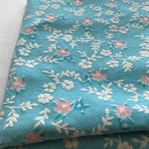 May include: A folded piece of blue fabric with a white and pink floral pattern.