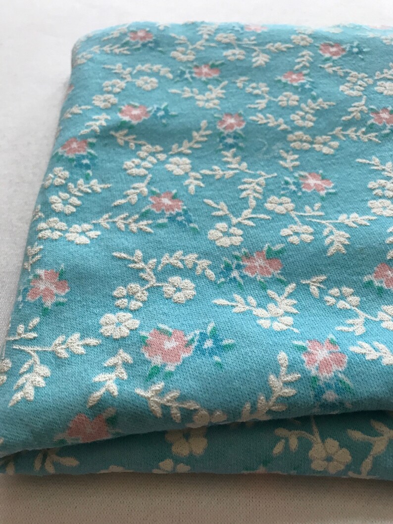 May include: A folded piece of blue fabric with a white and pink floral pattern.