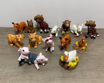 Puede incluir: Una colección de pequeñas figuras de animales, que incluyen un zorro, una ardilla, un caballo, un conejo, un mono, un guepardo, un tigre, un cerdo con gafas de sol, un toro, una gallina con pollitos y un pato con patitos.