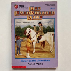 Peut inclure: La couverture du livre #54 du Club des Baby-Sitters présente un cheval blanc avec une fille qui le monte. Le titre du livre est "Mallory et le cheval de rêve" par Ann M. Martin.