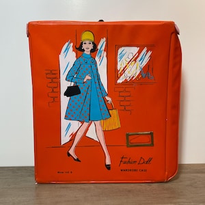 May include: A vintage orange Fashion Doll wardrobe case. The case has an illustration of a woman in a blue coat with red polka dots, a yellow hat, and a black purse. The text "Fashion Doll Wardrobe Case" is printed on the case.